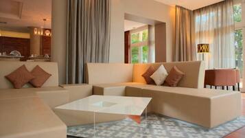 A modern living room with a sectional sofa, a glass coffee table, and a patterned rug.