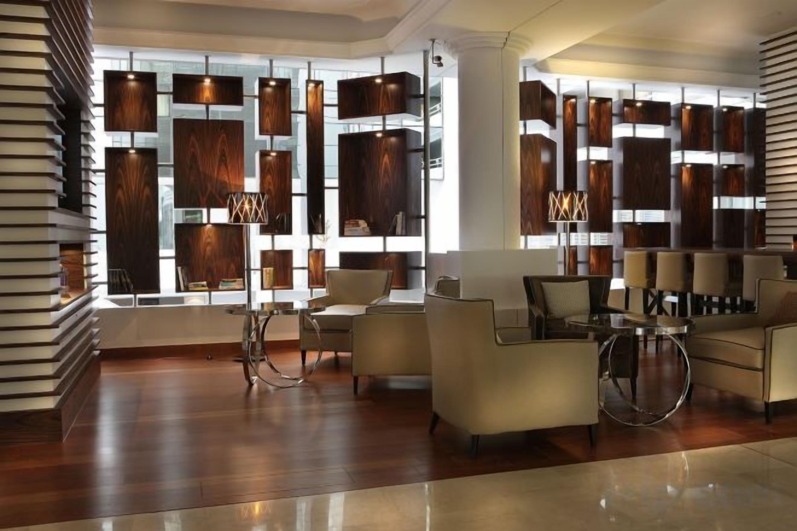 A modern lobby with a wooden wall feature, seating area, and a floor lamp.