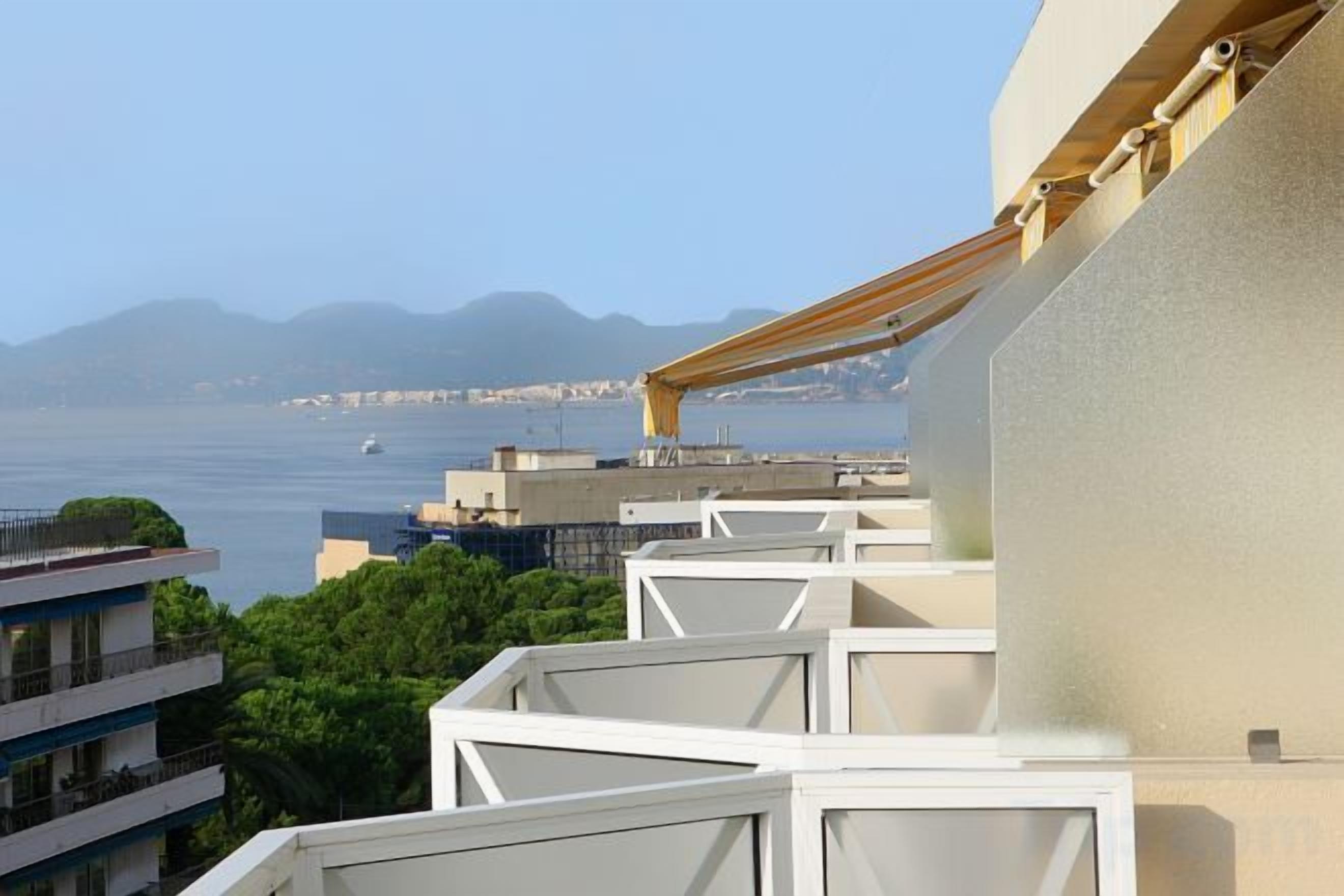 A balcony with a view of the sea and distant mountains.