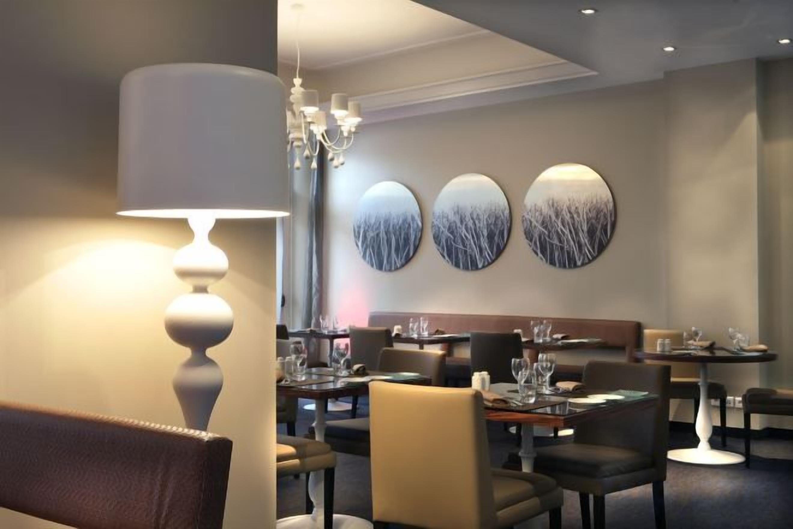 Ein Restaurantinneres mit Tischen, Stühlen und einer Chandelüstere.