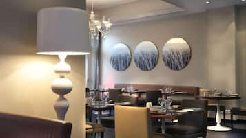 Ein Restaurantinneres mit Tischen, Stühlen und einer Chandelüstere.