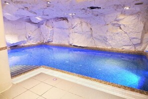 An indoor swimming pool with a tiled floor and a wall that appears to be made of rock or stone. - AC Hotel by Marriott Ambassadeur Antibes - Juan Les Pins (Juan-les-Pins)