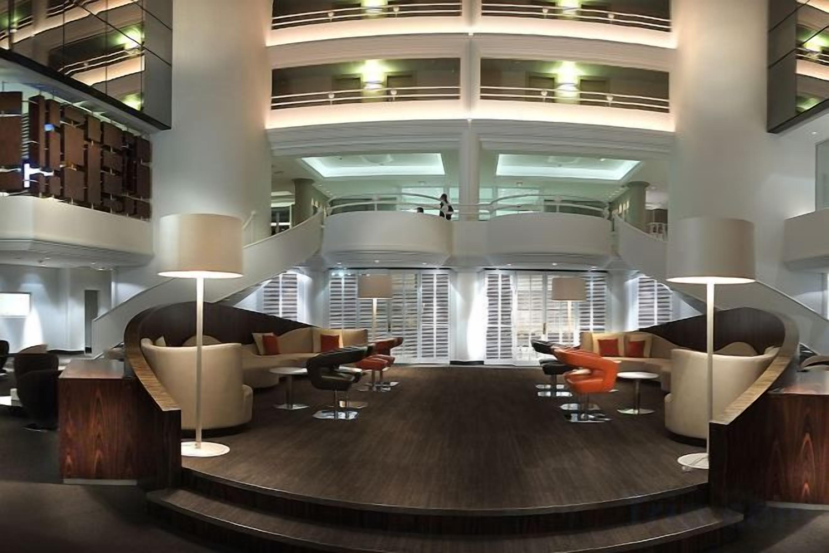 A multi-level lobby with a central seating area, a staircase, and a high ceiling.