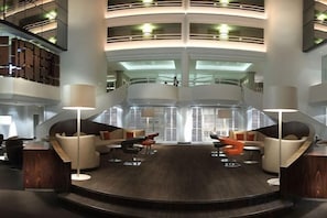 A multi-level lobby with a central seating area, a staircase, and a high ceiling.