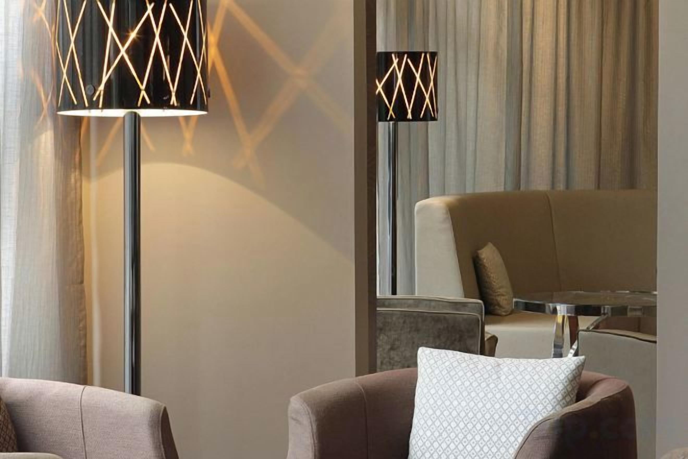 A modern living room with a sofa, a coffee table, and two floor lamps with geometric patterns.