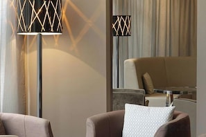 A modern living room with a sofa, a coffee table, and two floor lamps with geometric patterns. - AC Hotel by Marriott Ambassadeur Antibes - Juan Les Pins (Juan-les-Pins)