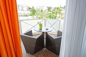 Ein Balkon mit Korbmöbeln, einem kleinen Tisch und einem Blumentopf.