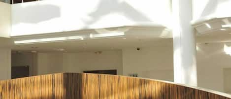 A modern interior with a curved wall, a seating area with a cushion, and a visible staircase.