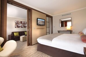 Een hotelkamer met een groot bed, een televisie, een bank en een bureau.