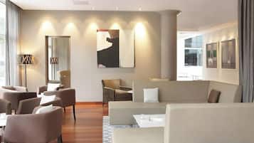 A modern hotel room with a seating area, a sofa, and a dining table.