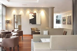 A modern hotel room with a seating area, a sofa, and a dining table. - AC Hotel by Marriott Ambassadeur Antibes - Juan Les Pins (Juan-les-Pins)