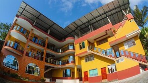 Un edificio de varios pisos con balcones, una entrada cubierta y una puerta roja.