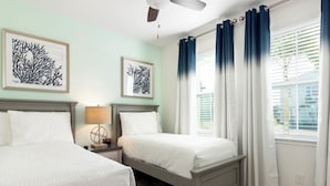 Une chambre avec deux lits, un ventilateur de plafond et des œuvres d’art accrochées aux murs.