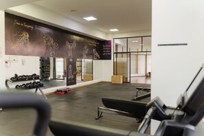 A gym with exercise equipment, a wall with motivational quotes, and a mirror.