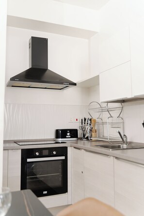 Una cucina moderna con mobili bianchi, forno nero, piani di lavoro in acciaio inossidabile e cappa aspirante nera.