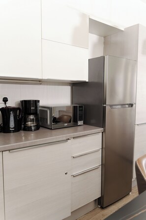 A modern kitchen with a stainless steel refrigerator, a microwave, and a coffee maker on the counter.