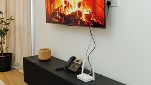 Un salon moderne avec un téléviseur à écran plat fixé au mur, qui diffuse une image de cheminée.
