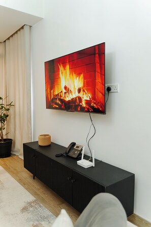 Un soggiorno moderno con una TV a schermo piatto montata a parete che mostra un camino.