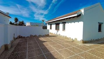 A white building with a tiled patio and a clear blue sky.