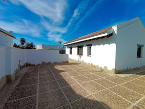 A white building with a tiled patio and a clear blue sky.