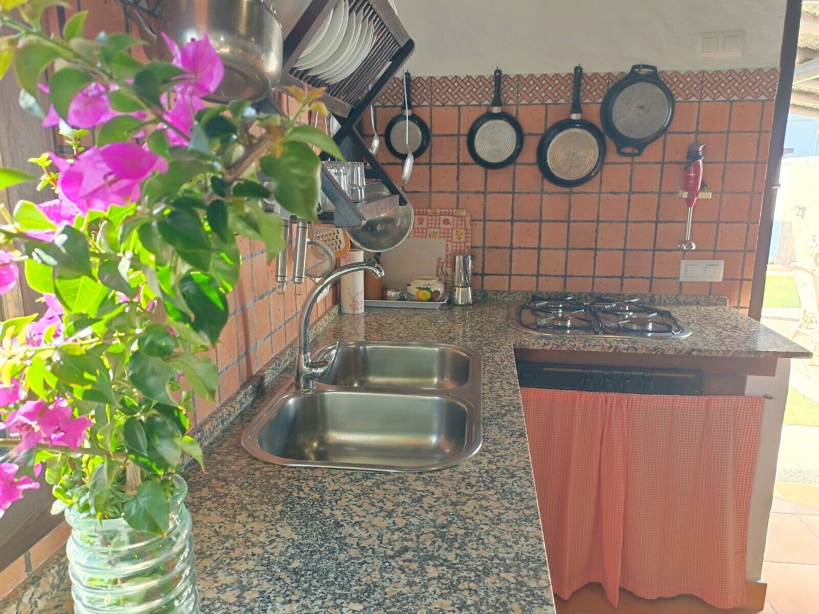 Una cocina con encimera de granito, pileta de acero inoxidable y cocina a gas.