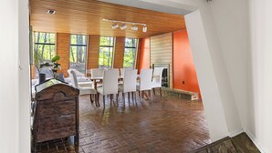 Un espace repas doté d’un sol en briques, d’un plafond en bois et de grandes fenêtres.