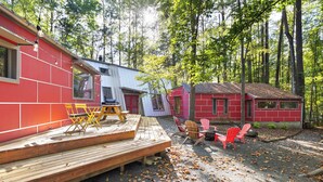 Un chalet rustique doté d’une terrasse en bois, de meubles d’extérieur et d’une façade rouge.