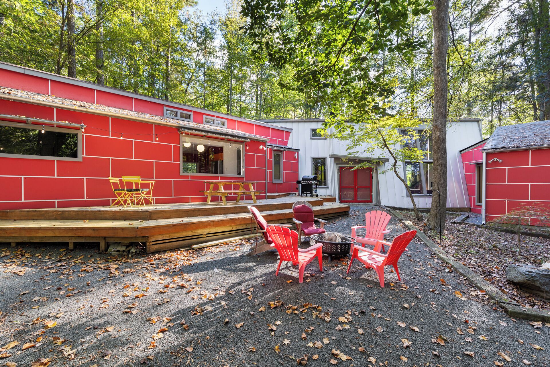 Ein rotes Gebäude mit einer Terrasse, Sitzgelegenheiten im Freien und einer Feuerstelle.