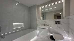 Une salle de bain moderne avec une douche à parois de verre, un lavabo en marbre et des toilettes.