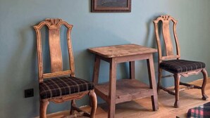Una stanza con due sedie di legno dotate di sedili imbottiti, un piccolo tavolino e due lampade fissate al muro.