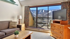 A modern living room with a large sliding glass door leading to a balcony with a mountain view. - Mountain Green Resort (Killington)
