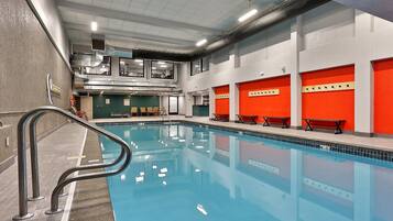 An indoor swimming pool with a clear water surface, surrounded by walls with red and white panels, and a ceiling with visible lighting fixtures.