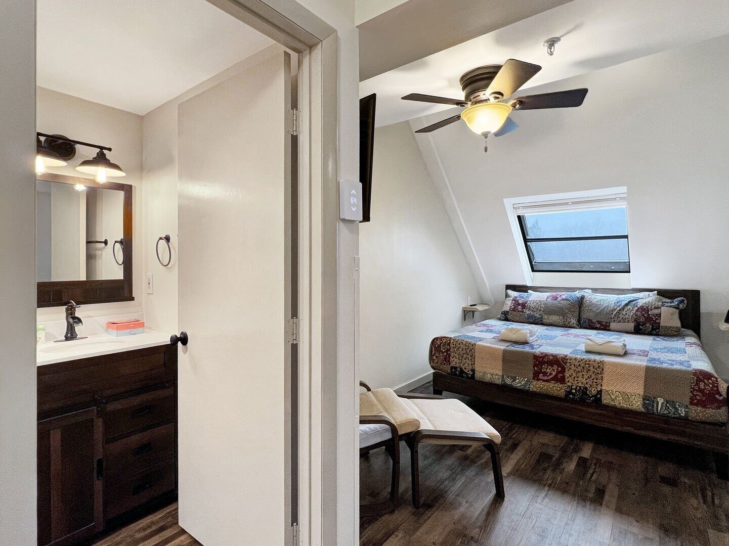 Een slaapkamer met een bed, een plafondventilator, een raam en een nachtkastje.