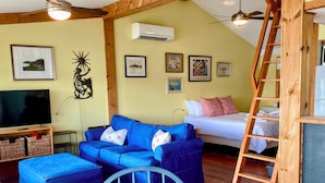 A cozy room with a blue sofa, a bed, a TV, and a ladder. - Water Lovers Retreat: stunning water views - dolphins for neighbors (Peletier)