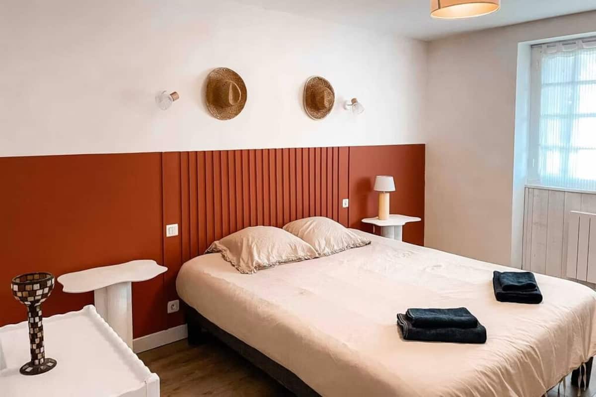 A hotel room with a bed, a nightstand, a lamp, and two wall-mounted decorative items.