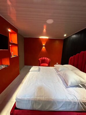 Een moderne slaapkamer met een bed, een rode fauteuil en inbouwkasten.