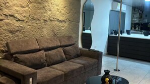 Una sala de estar moderna con un sofá marrón, una mesa de centro redonda y una pared con textura.