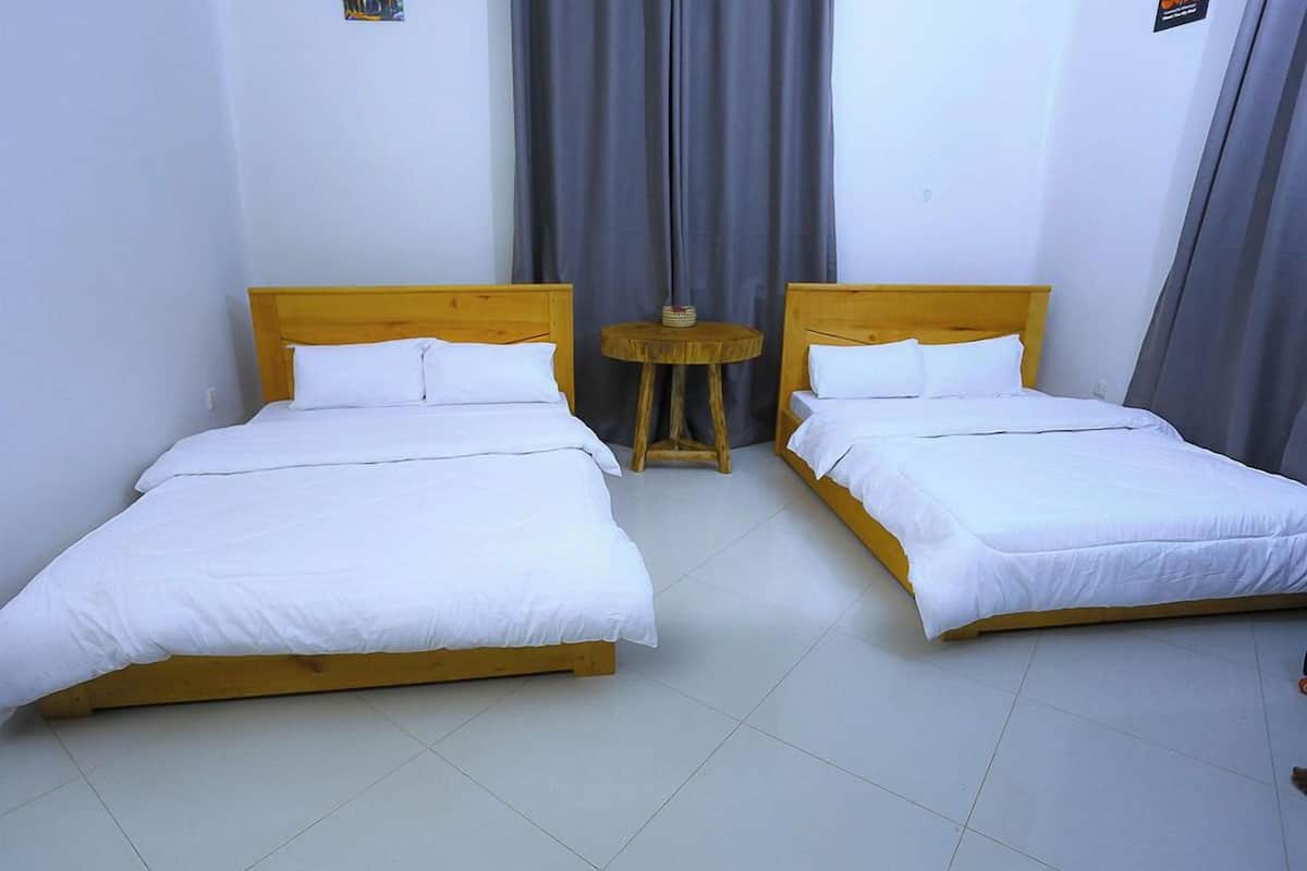 A room with two single beds, a small round table, and grey curtains.