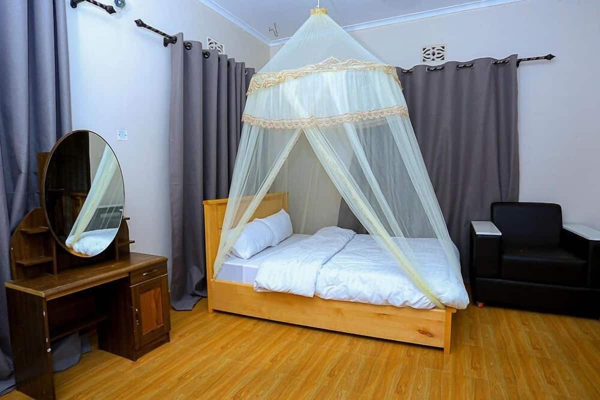 A bedroom with a wooden bed, a bedside table, a mirror, and a canopy bed.