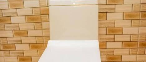 A toilet with a white tank and seat, set against a tiled wall with a wood-like pattern.