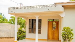 A building with a covered porch, a wooden door, and a small potted plant.
