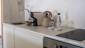 Eine moderne Küche mit Backofen aus Edelstahl, einer eingebauten Mikrowelle und einer Kaffeemaschine.