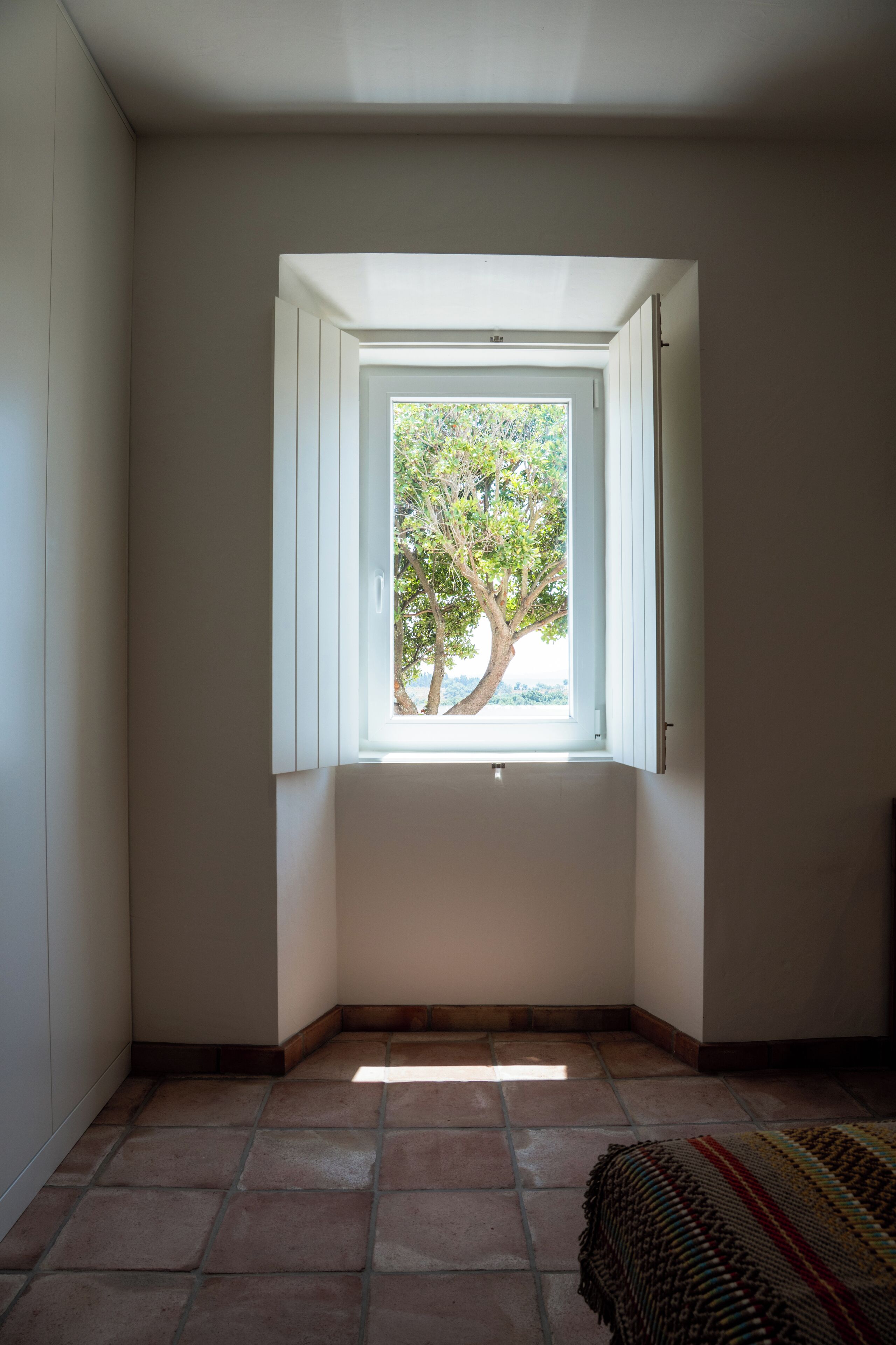 Ein Zimmer mit Fenster, Fliesenboden und Tür.