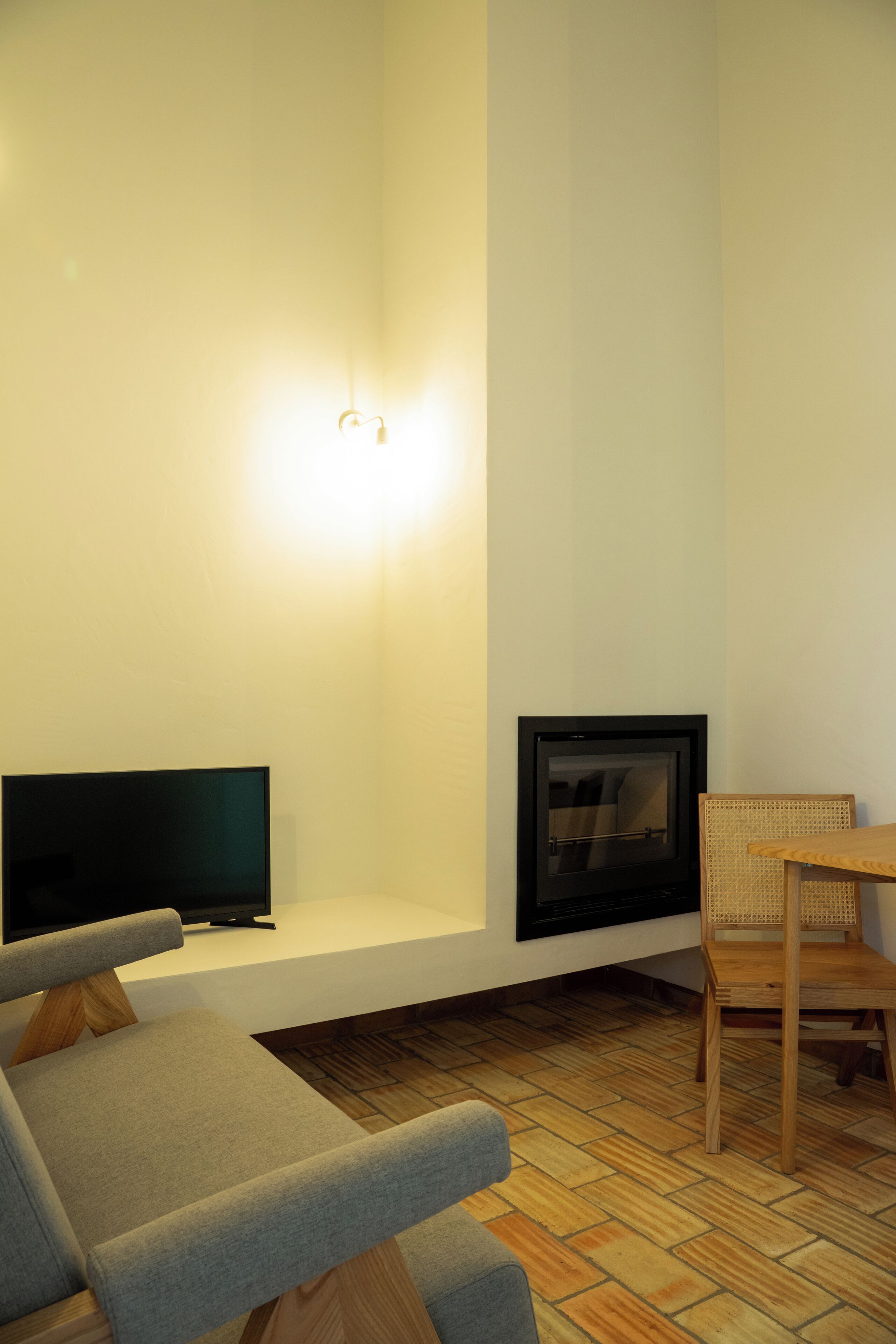 A modern living room with a flat-screen TV, a fireplace, and a wooden dining table.
