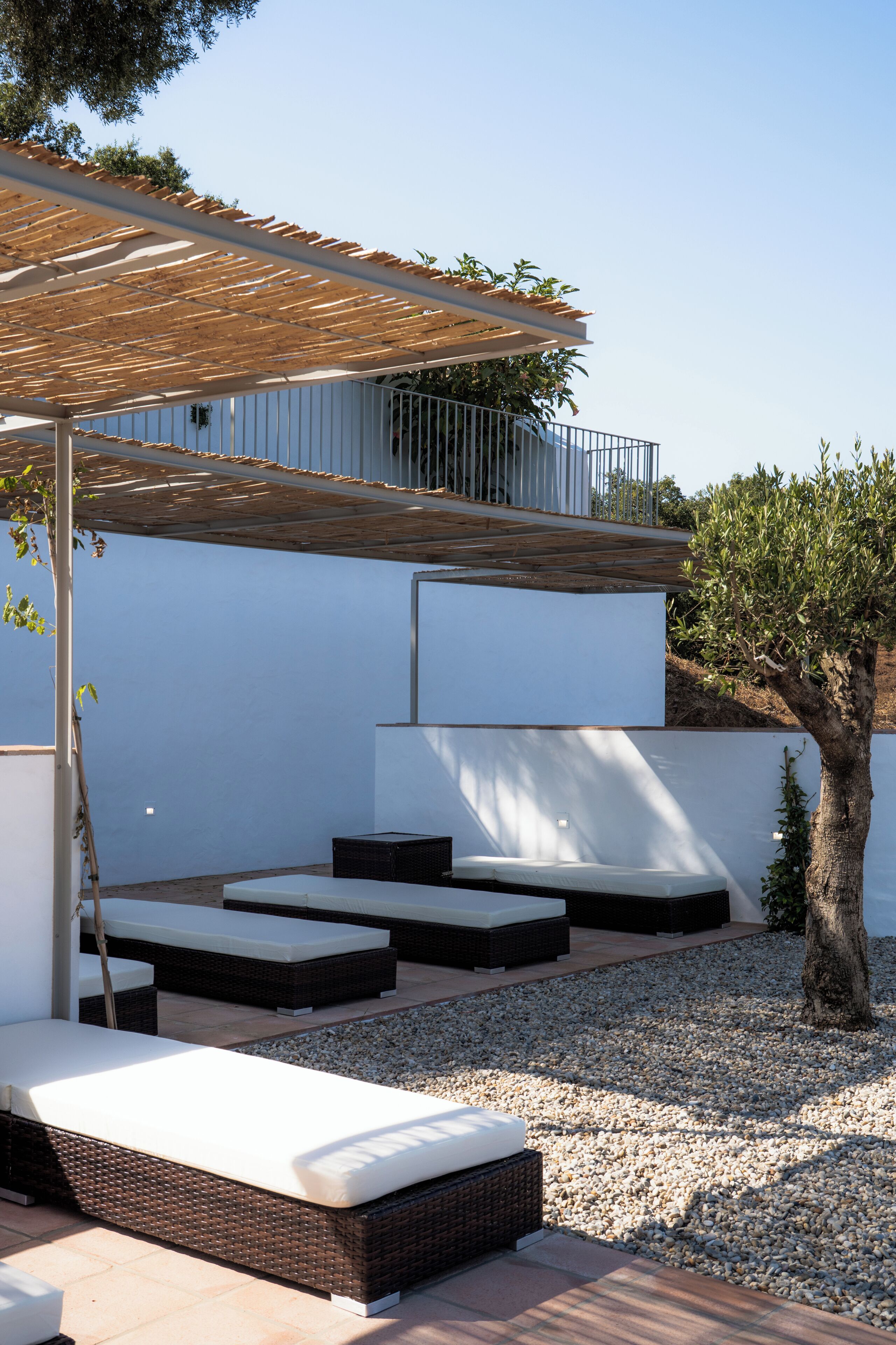 Un área de estar exterior moderna con sillones de mimbre y una pérgola.