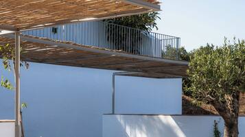 Un área de estar exterior moderna con sillones de mimbre y una pérgola.