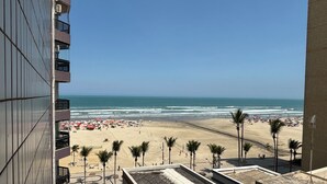 A beach view from a high-rise building with a clear sky, palm trees, and a sandy beach. - Apartment 57, Air Conditioning, Sea View, WiFi, Parking Space, Complete. (Praia Grande)