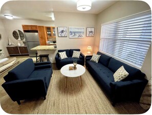 A living room with two sofas, a coffee table, and a kitchen in the background.