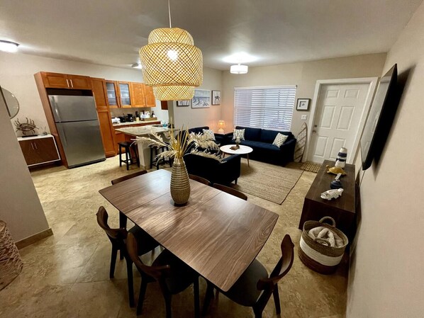 A modern kitchen with a refrigerator, wooden cabinets, and a dining area with a table and chairs.