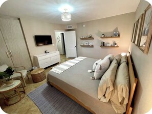 A bedroom with a bed, bedside tables, a television, and a wardrobe.